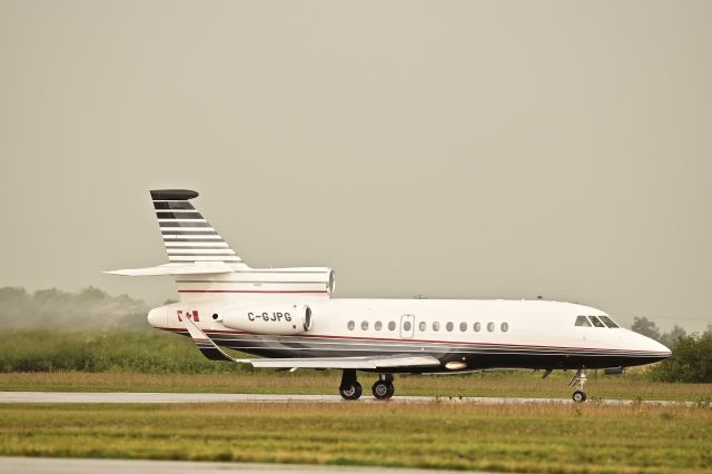 Dassault Falcon 900 (C-GJPG) - Water splashes off the tail and is vaporized as it hits the jet blast of this Falcon as it begins its takeoff roll from Yorkton on its way to Edmonton