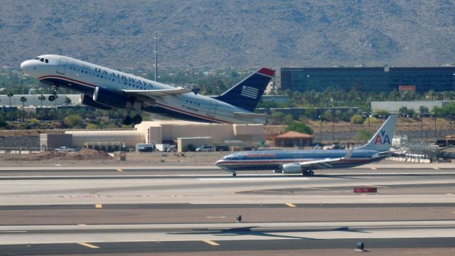 Airbus A319 (N833AW) - A US Airways A319 takes off as an American 737 rolls out.