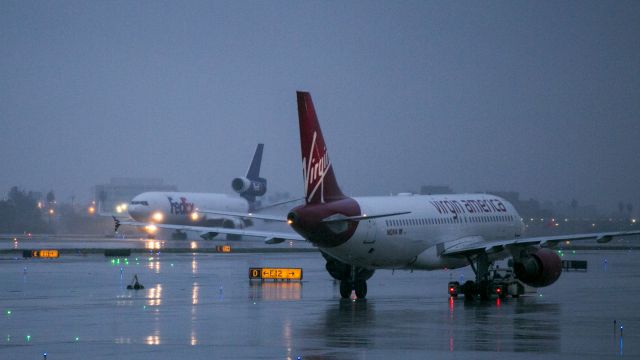 Airbus A319 (N624VA) - Early morning LAX. This Virgin A319 waits patiently for its gate to open as a FedEx freighter lands during a heavy Pacific storm in Los Angeles, California USA. 12 Dec 2014