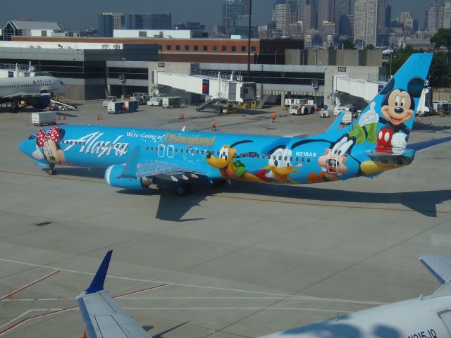 Boeing 737-700 (N318AS) - Disney themed B737 N318AS cheers up the Terminal A ramp at Logan Airport Boston July 17th 2013. Tug free 318 gets ready to taxi as ASA25 to Seattle