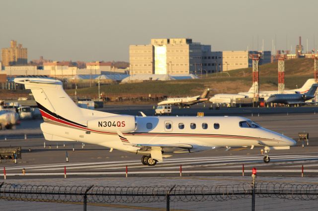 Embraer Phenom 300 (N304QS) - New York LaGuardia (LGA). Built in 2013 and owned by Oklahoma OK based fractional jet operator NetJets (1I).  Pictured catching the final rays of winter sunshine prior to take off taken from Planeview Park, 23rd Avenue at the end of Runway 4/22br /2017 11 29  a rel=nofollow href=http://alphayankee.smugmug.comhttps://alphayankee.smugmug.com/a