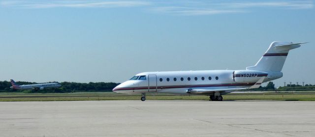 IAI Gulfstream G280 (N502RP) - Catching some tarmac time is this 2018 Israeli Aircraft Industry Gulfstream 280 while N153AN American Airlines Airbus is about to land on the active runway in the Summer of 2021.