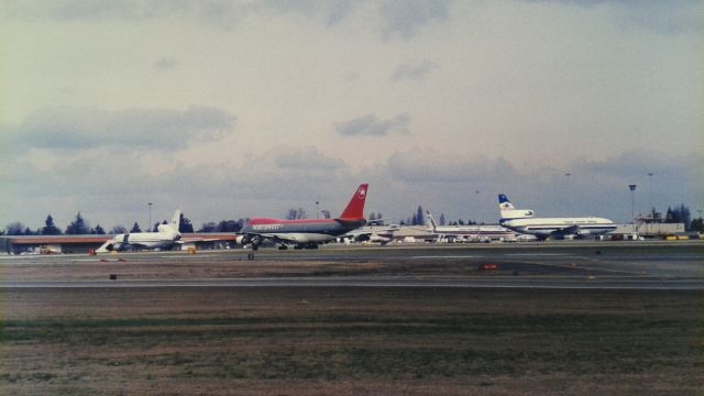 Boeing 747-200 — - KSEA - looking NNE at Bow Lake on Feb 27th, 1995 as a NWA 747-2 idles for departure hold bars, the cargo ramp in the background always had some sort of jet or piston engine aircraft Id never seen before every time I was in Seattle. Photo from the now closed and long gone Airpark - this is the 3rd runway west area now. Click full.