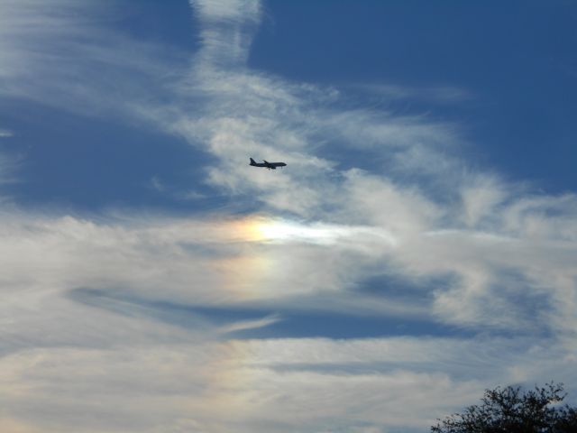 — — - Plane flying into Tampa International Airport above a rainbow through the clouds.