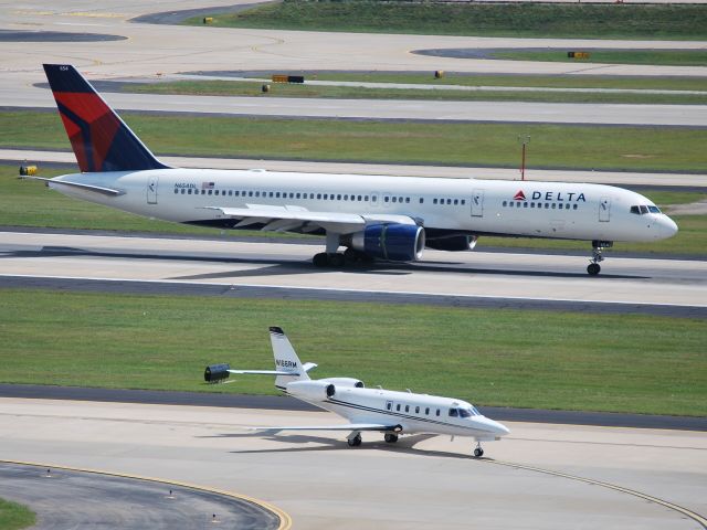 Boeing 757-200 (N654DL) - Arriving runway 26R while N166RM taxis to the Atlantic FBO - 8/22/09