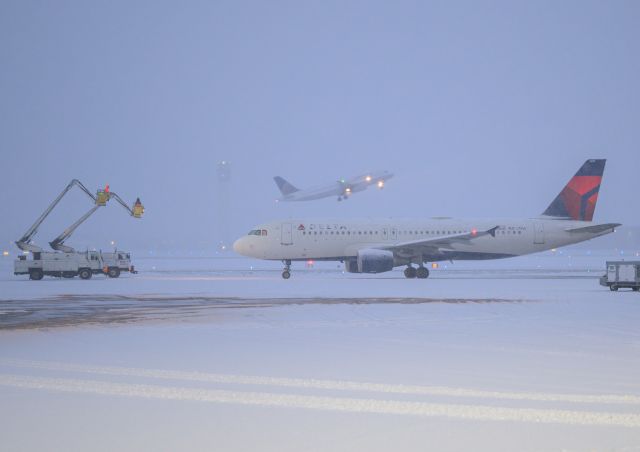 Airbus A320 (N357NW) - DELTA GETTING READDY TO BE DEICED AS UA TAKING OFF IN SNOW FALL