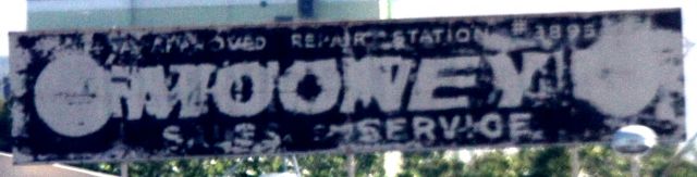 — — - MOONEY SALES AND SERVICE sign atop a building at KSJC .. SE side of airport . Estimated: Circa 1940s  . Quality of Image, based upon condition of sign