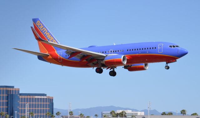 Boeing 737-700 (N7730A) - N7730A seen here just before touchdown on runway 20R. A pretty difficult noontime shot in 90 degree temperatures last month. Looks like it should be due to get the new paint job pretty soon because the blue looks a bit faded (at least the paint isnt peeling off like Ive seen on some other SWA birds lol)