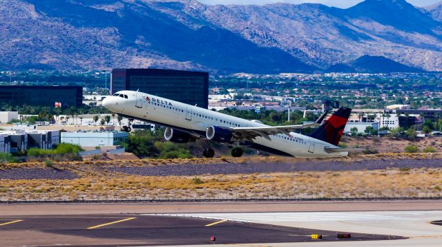 Airbus A321 (N119DN) - American Airlines A321 taking off from PHX on 8/20/22. Taken with a Canon 850D and Rokinon 135mm f/2 manual focus lens.