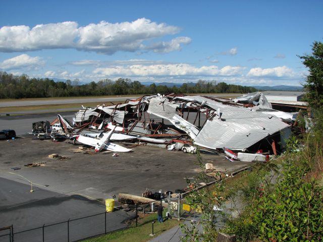 — — - Tornado hit the area the evening before. Multiple aircraft damaged, several destroyed. All aircraft were inside the hanger but the high winds peeled the top off, exposing everything! Steel beams pulled out of the ground... note the holes in the asphalt.