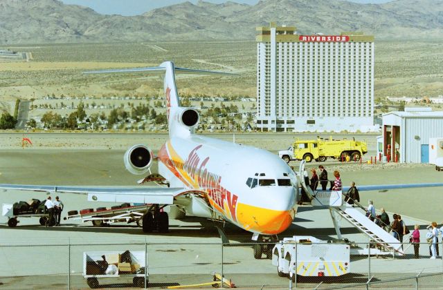 BOEING 727-200 (N284SC) - KIFP - Feb 1998 Sun Country 727-2 loading pax after a weekend junket to Laughlin,NV Casinos in the background. This photo taken in Arizona, at Laughlin-Bullhead City,AZ Airport. The time difference is 1hr across the Colorado River along the lower tree line this time of year, in front of the Riverside Hotel. This jet headed to MSP with a lighter load - wallet wise. CN:21438 LN: 1301. The Riverside Casino? The top floor glassed penthouse, is actually an apartment for the last holdout who lived along the river and would not sell her property to the Casino. So they promised to build her a Top Floor apartment and she could live there till she died. That sealed the deal, and that is why that apartment is atop the building!.