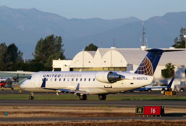 Canadair Regional Jet CRJ-200 (N507CA) - KRDD - Skywest United Express blasting down Runway 16 for SFO - passing the Redding Smoke Jumper/Air tanker base complex off the right wing. This RJ sat at the hold bars for almost 30 mins before departing. click full