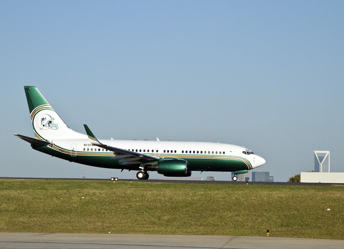 Boeing 737-700 (N737WH) - "Clean and green," this Boeing 737 is painted with the Miami Dolphins football team logo on the tail departs from Charlotte, North Carolina on Thursday evening, 21 Oct 10. Check out the other photos of this plane for nice pictures of its interior. Plenty of plush seating. Downtown Charlotte is in the background, the triangular shaped building is the Duke Energy Center.