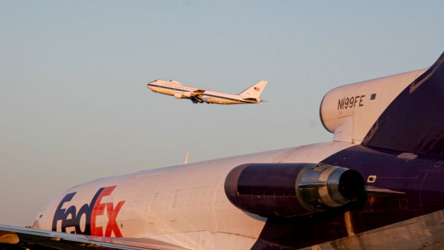 Boeing 727-100 (N199FE) - An E-4B takes to the skies over the frame of an old FedEx 727 in Wichita