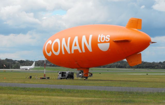 Unknown/Generic Airship — - Shown here promoting his late night Television show is the Conan (O'Brien) Airship from the Autumn of 2010. Bottom left shows a visiting Boeing 737 catching some Tarmac time.