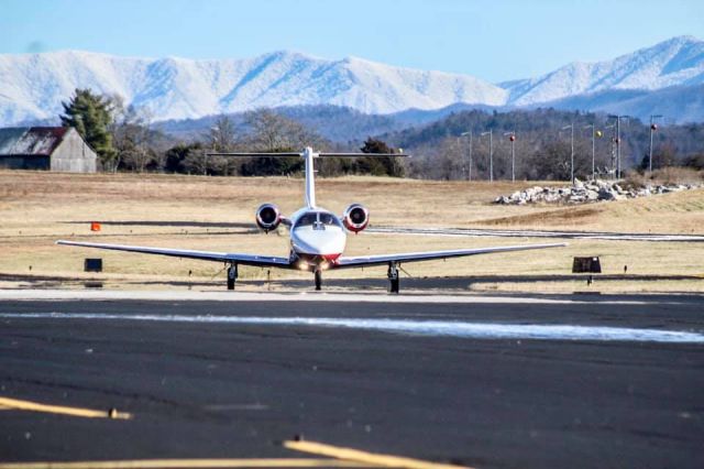 Cessna Citation CJ2+ (N878JP) - N878JP taxiing to the FBO after landing on R10. Complete with the snow covered smokies in the background.