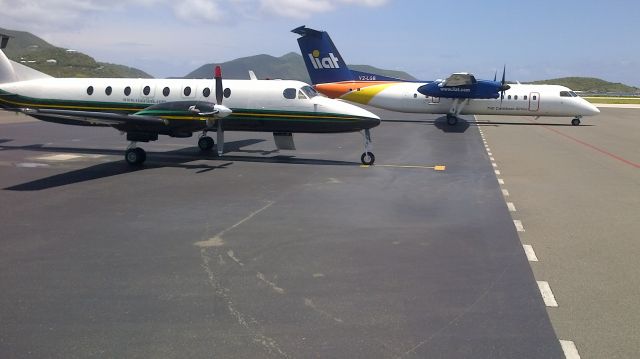 Beechcraft 1900 (VP-LVI) - Left hand view parked next to a Dash 8