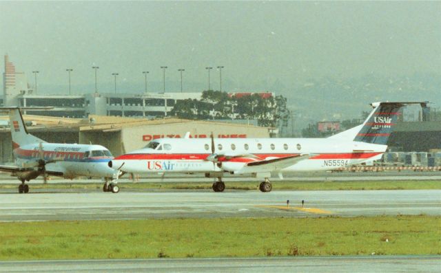 Beechcraft 1900 (N55594) - KLAX - Sept 1989 US Air Express ( with a fake PSA smile) set to depart 25L at Los Angeles. Airline departures from 25L were very rare back in the 1980s. 25R was not being used this day so I'm sure a maintenance issue was at hand. photo from the FedEx parking lot at LAX. I had an 8ft ladder I took with me in my truck to clear the fence.