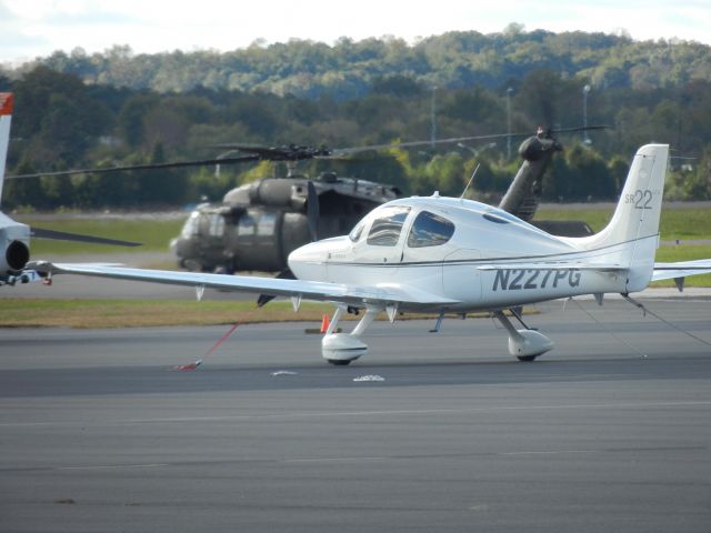 Cirrus SR-22 (N227PG) - A SR-22 Is Parked On The Ramp While A U.S Army UH-60 Blackhawk Taxies To Runway 34 Right In The Near Distance