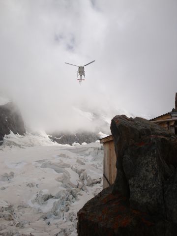 — — - A search and rescue helicopter approaches our hut after retrieving some injured and stuck climbers on Mont Blanc.