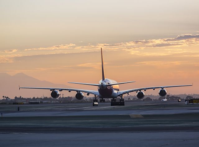 Airbus A380-800 (VH-OQK) - Here comes the sun-this big Qantas Kangaroo has just landed and is taxiing into the sunrise. Its destination is the international terminal at LAX, Los Angeles, California USA