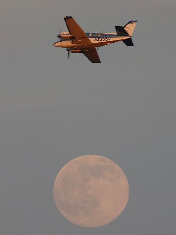 Beechcraft 55 Baron (N22334) - Beech Baron flying over the moon at sunset.