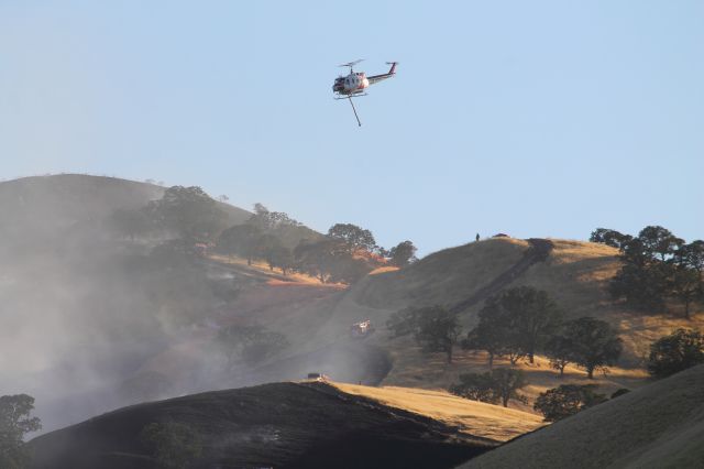 — — - While crews attack the fire below, a Super Huey attacks from above.