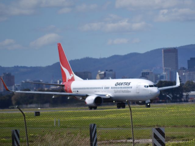Boeing 737-800 (VH-VXE) - On taxi-way heading for take off on runway 05. Part of the Adelaide city skyline is visible in the background.