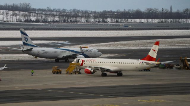 Embraer ERJ-190 (OE-LWN) - 12/7/23  parked on hard stand with a passing El-Al B737-8