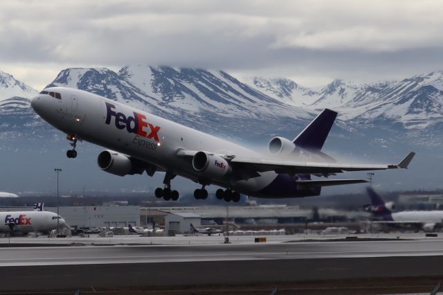 Boeing MD-11 (N596FE) - Takeoff with wing condensation clouds, viewed from the west side of Runway 15-33