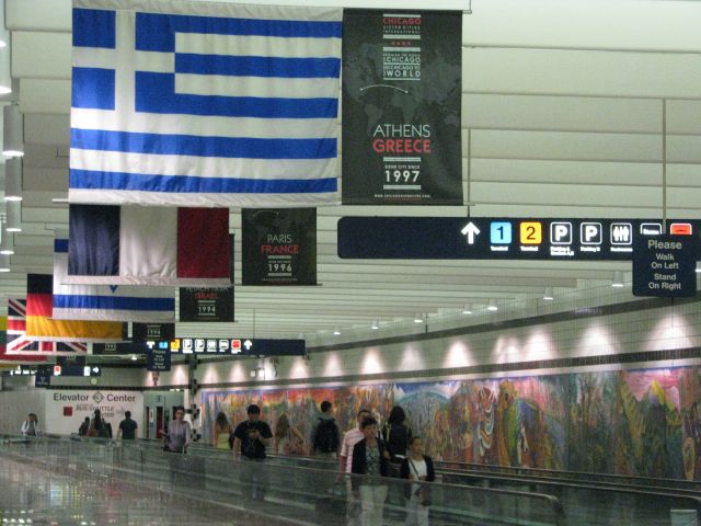 — — - The ORD pedestrian walkway, THE link between ORD airport terminals 1 through 3 and what used to be terminal 4, but is now the shuttle transportation center. Here we see the City of Chicago Sister Cities flag project