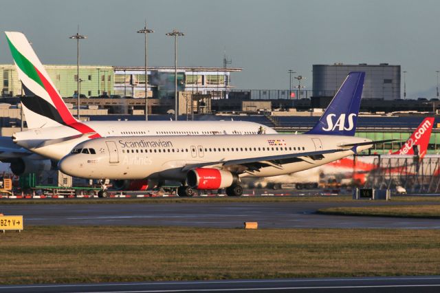 Airbus A320 (OY-KAU) - SAS539 arriving from Copenhagen as the EK A380 gets deiced in the background.