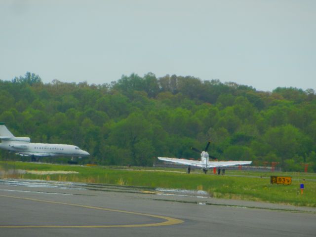 North American P-51 Mustang (N151AM) - N151AM, Andrew McKenna's private P-51 Mustang, taxies out the runway as N711FJ, a Dassault Falcon 900, holds short of the runway