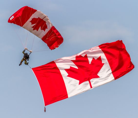 — — - A member of the Canadian Armed Forces Parachute Team, the SkyHawks, flies the Canadian flag at the opening ceremonies of Airshow London 2017