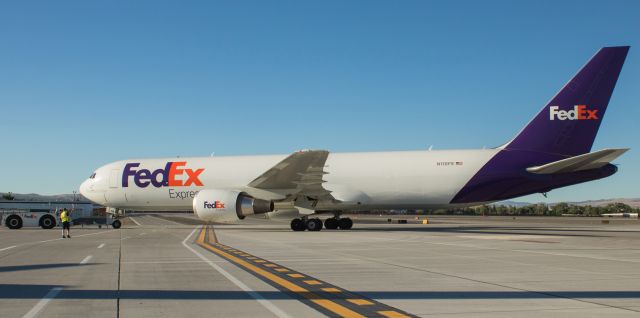 BOEING 767-300 (N118FE) - A ground crew wing walker signals to the tug operator that there are no obstructions as Fed Exs "Emilee," a B763 (N118FE), is being pushed back from the cargo ramp to a "tail south" position on RNOs Alpha taxiway in preparation for a 7:00 PM departure to Memphis.