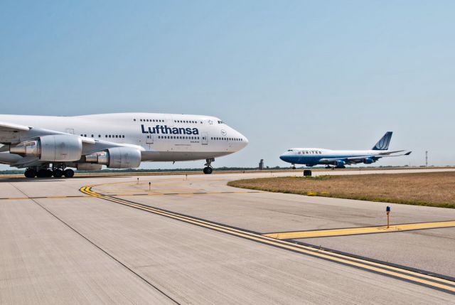 Boeing 747-400 (D-ABTB) - UAL B744, N199UA lines up for departure on RWY 7 as Lufthansa B744 D-ABTB taxies for departure after being diverted to RFD during storms at ORD last summer