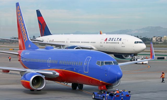 Boeing 737-700 (N292WN) - A pair of pushbacks .... As a tug is pushing back SWAs N292WN from a Southwest gate for a morning flight to San Jose, another tug is pushing a DAL B772 (N709DN) from a Delta gate.