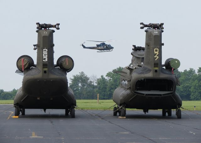 — — - Two Boeing CH-47 Chinooks waiting modifications while a Delaware State Trooper Bell 407 goes through maneuvers.