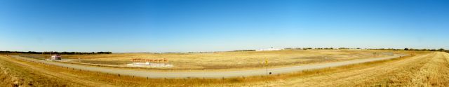 — — - Panoramic view of the airport. Standing on berm at the south end of the runway looking north.