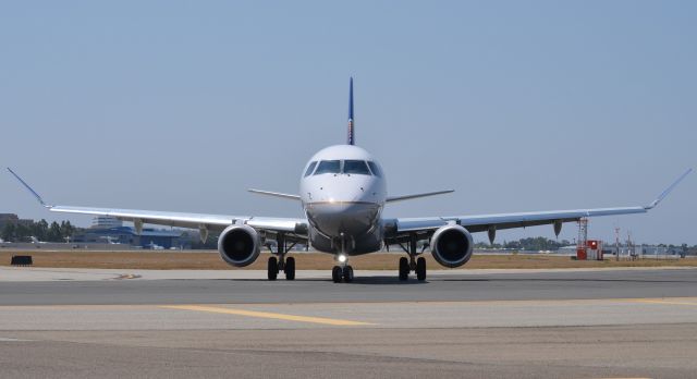 Embraer 170/175 (N161SY) - This E175 was delayed for about 20 minutes on the ground and is seen here in the spot that is used as a kind of holding area which is off to the right of runway 20R on taxiway "bravo". It is always nice from a photographers prospective because they get really close and usually stop for a while, making for a large window of up close photos. It is a complete experience because when they go to the runway from here they make a right turn which puts this spot directly behind them and you get a good amount of "jet blast" (I lost a perfectly good soda I had sitting on the wall).