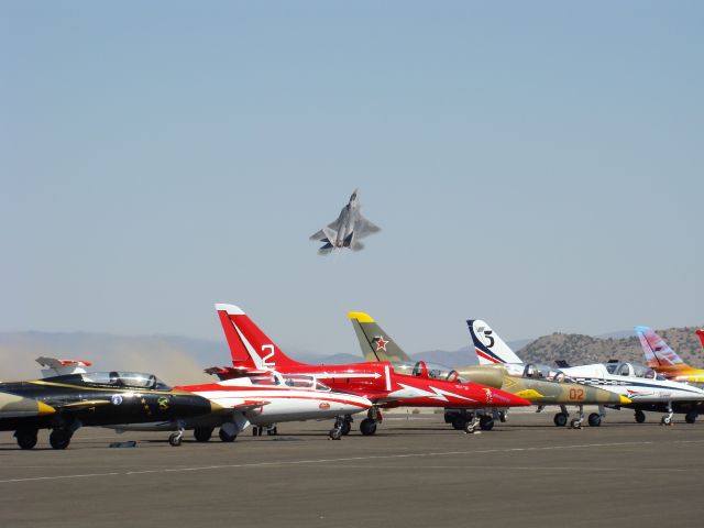 Lockheed F-22 Raptor — - F-22 Raptor Demo takes off at Reno with Jet Class aircraft in foreground.  Note the dust blown by the Raptors exhaust during rapid pull up at the end of the runway.