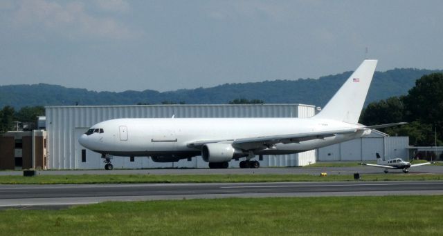 BOEING 767-200 (N795AX) - Taxiing for departure is this 1985 Cargo Aircraft Mgmt. Boeing 767-281 in the Summer of 2021. The Piper Cherokee N4121R awaits take-off clearance as the cargo jet passes behind it.