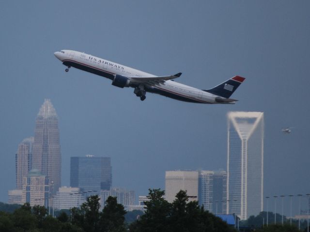 Cessna Citation Excel/XLS (KCLT) - A US Airways A330 departs 36R with downtown Charlotte in the background and heavy storms to the south east of the airport - 7/19/12