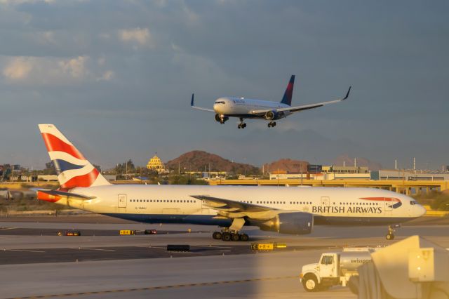 Boeing 777-200 (G-YMMJ) - British Airways 777-200 on the tarmac at PHX on 3/6/2022, with a Delta Airlines 767-300 landing in the background. Taken with a Canon 850D and Canon 75-300mm lens.