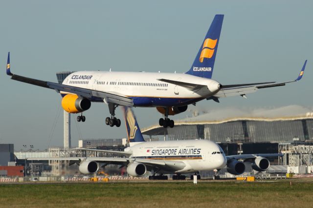 Boeing 757-200 — - An Icelandair B757-200 approaches runway 027L at LHR, with an Airbus A380-800 of Singapore Airlines in the background, taxiing out to the parrallel runway 027R to take off, bound for Singapore.