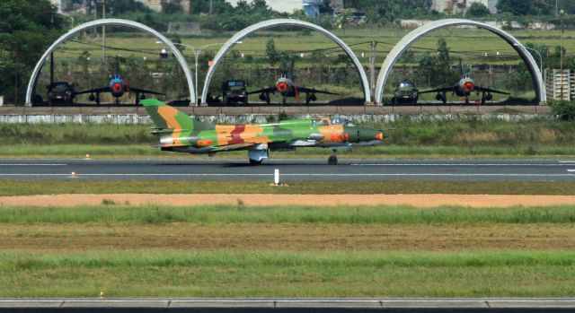 — — - Vietnamese Air Force Mig 21 taking off adjacent to Hanoi International Airport.  Half-round concrete shelters for Air Force palnes in background.