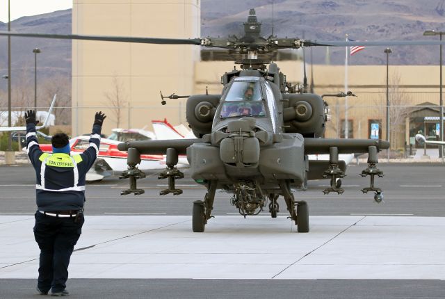 Boeing Longbow Apache — - As both pilots use their IHADSS (Integrated Helmet And Display Sighting System) to view him, an Atlantic Aviation agent marshals an Apache helicopter to a ramp parking position. However, since their IHADSS system allows them to aim that M230 Chain Gun cannon merely by looking at their target, perhaps that agent is not marshaling ... maybe he is surrendering.