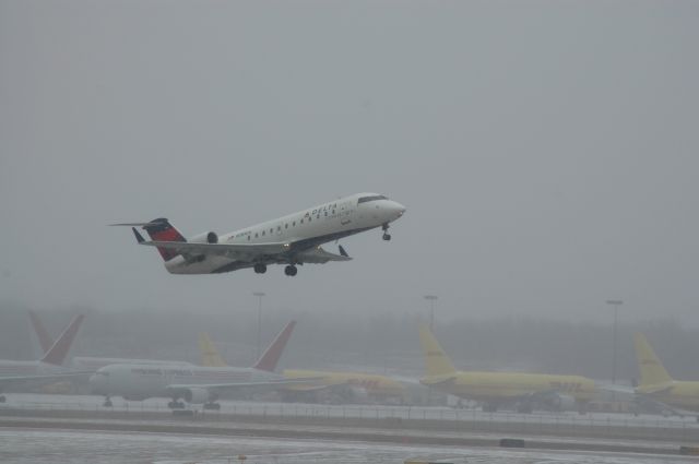 Canadair Regional Jet CRJ-200 (SKW4523) - departing from 36R at KCVG on a sat afternoon with some light snow, DHL ramp in the backround    Flight # SKW4523  N781CA