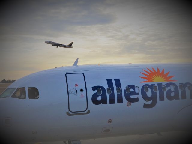 Airbus A320 — - Jetbridge while a Frontier A320 takes off in the background.