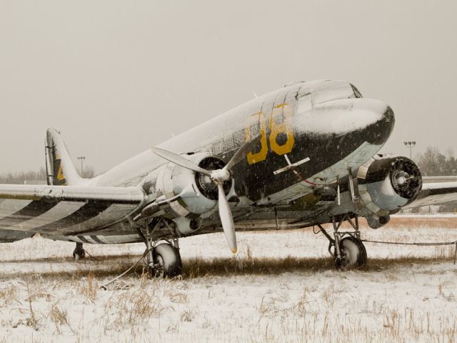 Douglas DC-3 (N12907) - A study in seasons: This derelict DC-3 (built in 1945) sits in a weedy patch just off runway 36R in Charlotte, North Carolina USA. Covered with snow and neglect, this old warbird patiently waits to feel the throb of its motors and air flowing over its wings. (photo taken Sunday, 26 Dec 2010)